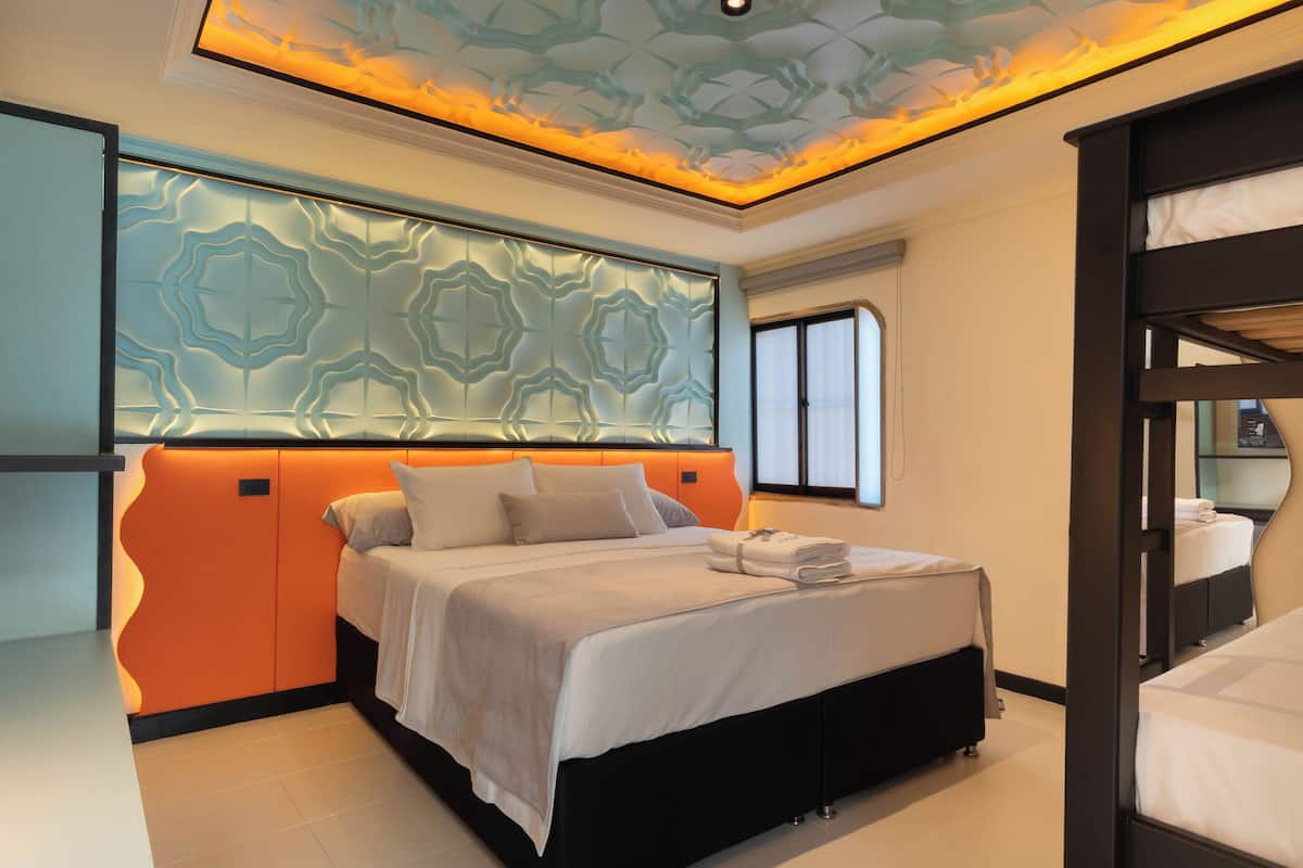 Une chambre à coucher moderne, dotée d’un grand lit, d’une tête de lit ornée d’un motif géométrique et d’un plafond au design original.