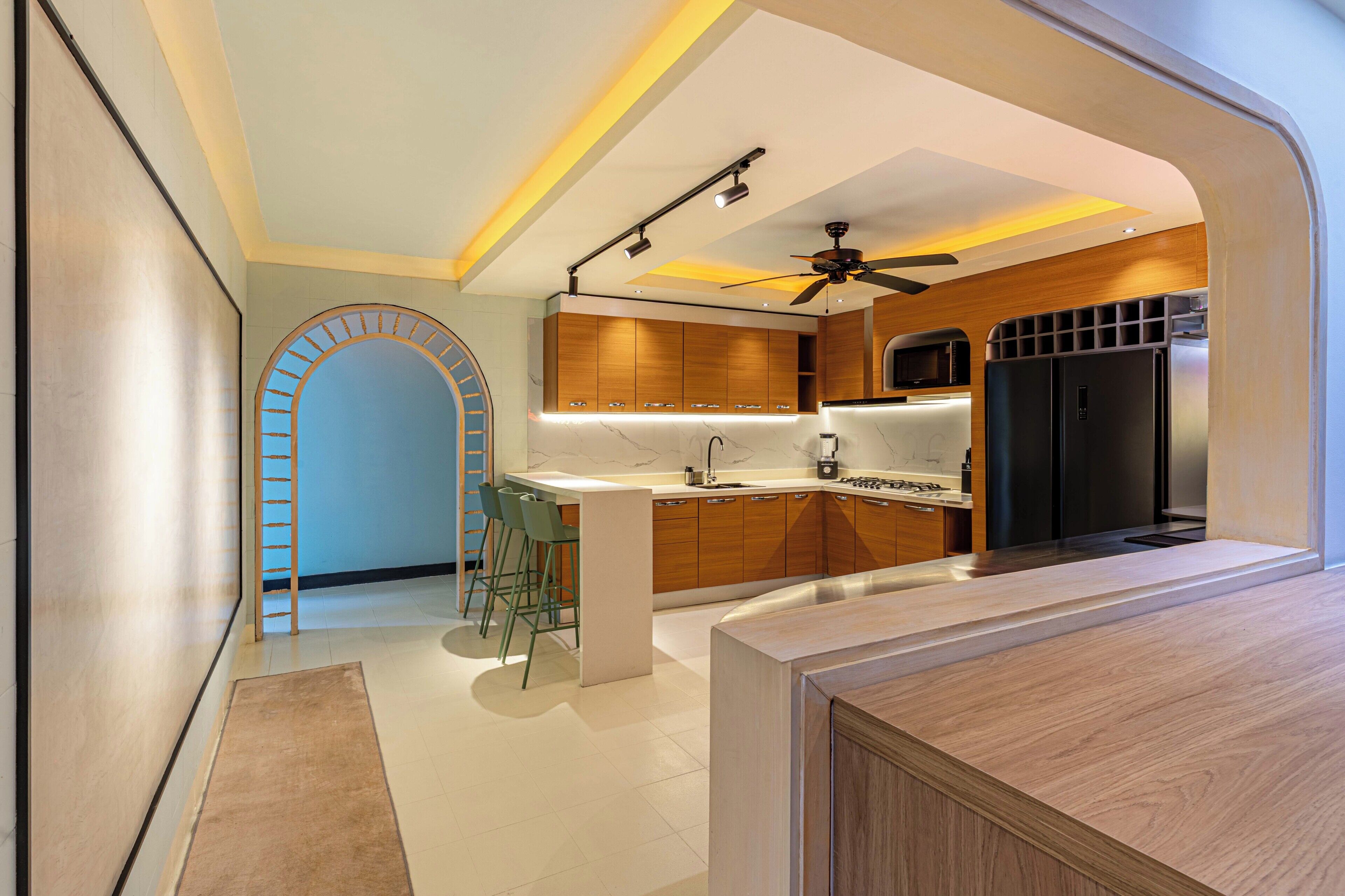 Una cocina moderna con armarios de madera, microondas integrado y un refrigerador negro.