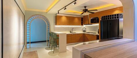 Una cocina moderna con armarios de madera, microondas integrado y un refrigerador negro.