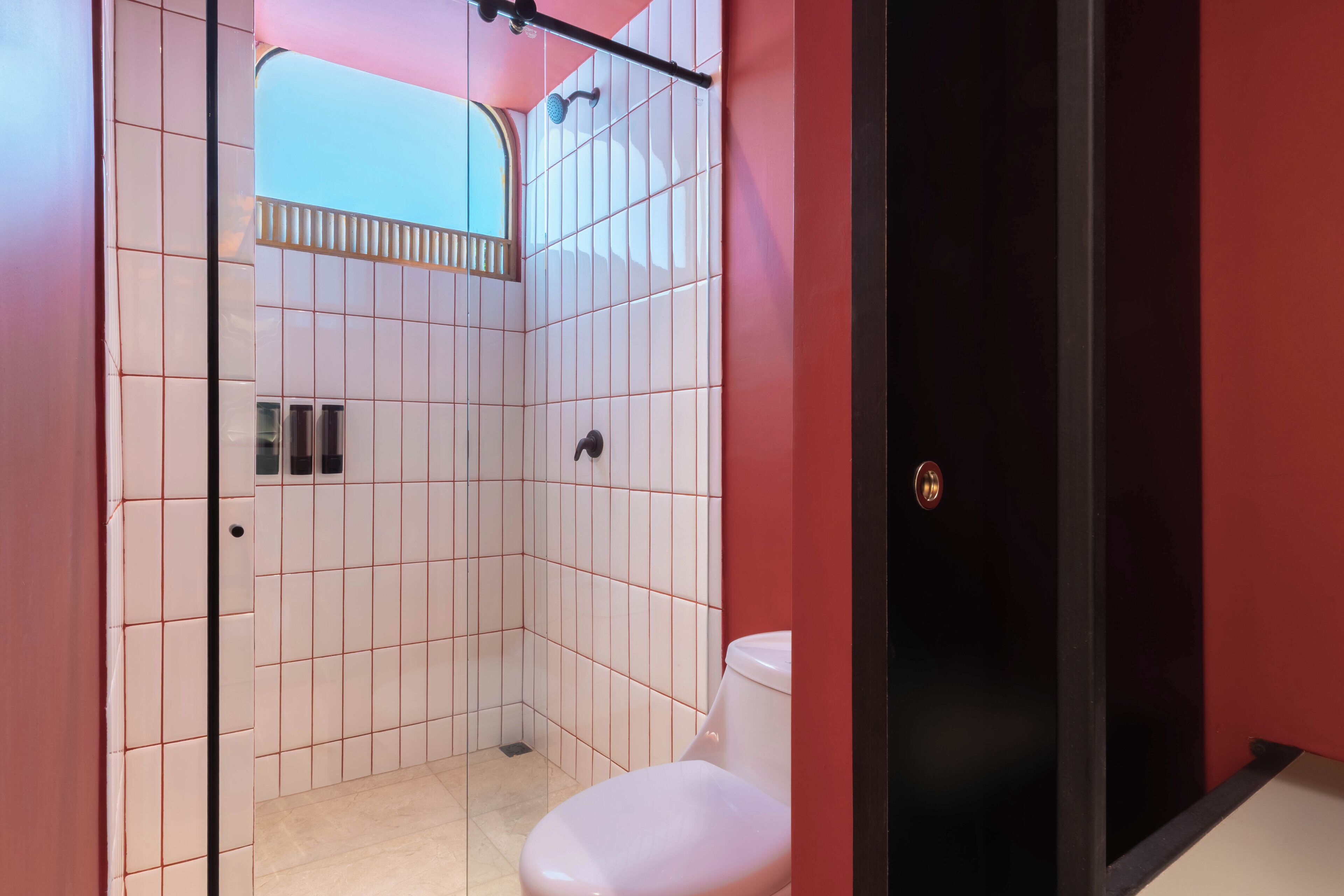 Um banheiro moderno com azulejos brancos, chuveiro e vaso sanitário.