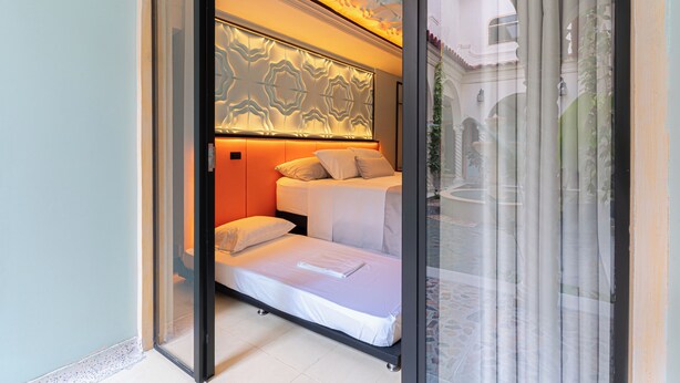 Una habitación con una cama, cabecera con diseño geométrico y una ventana con cortinas.