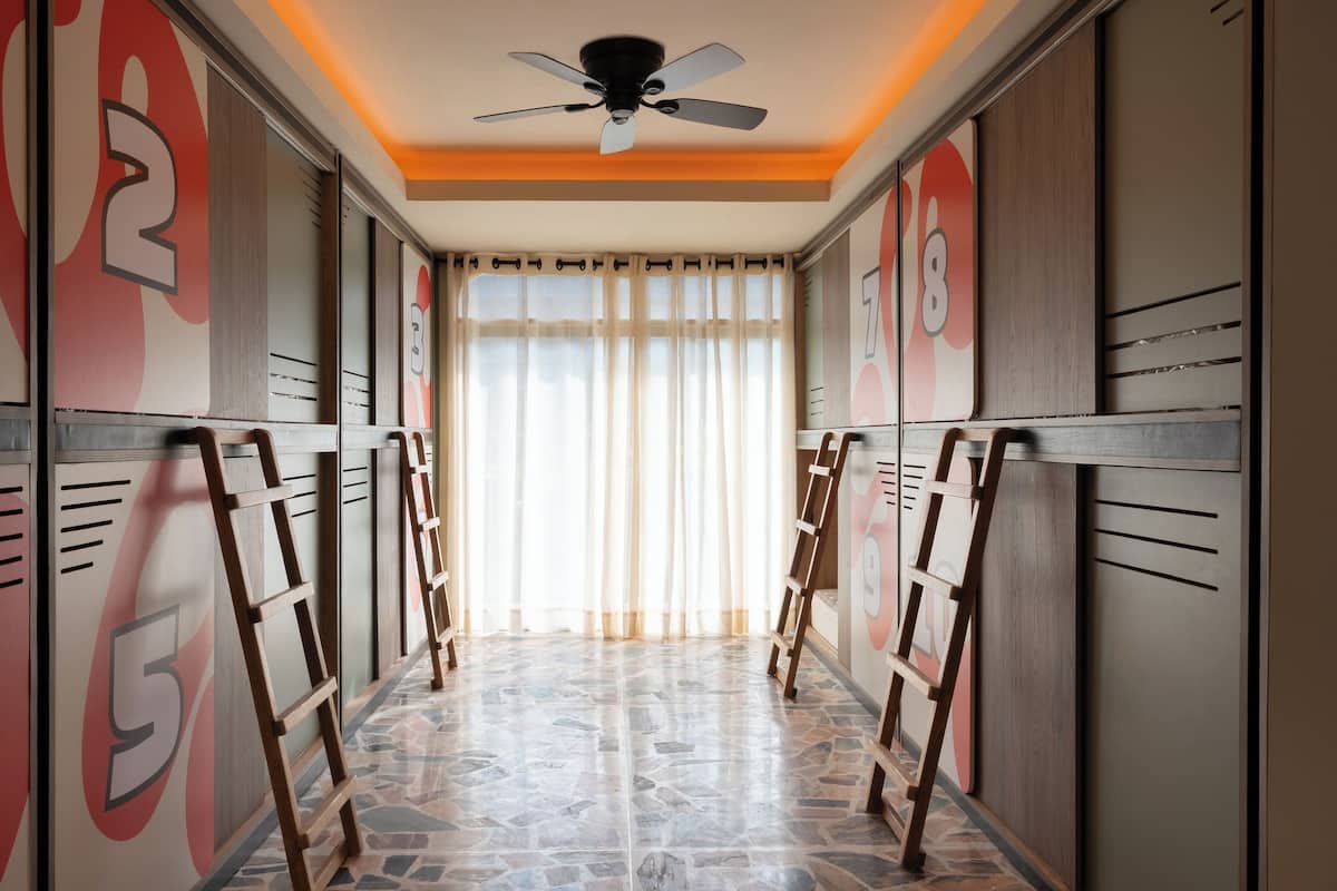 Un couloir avec des casiers, un ventilateur de plafond et une fenêtre avec des rideaux.
