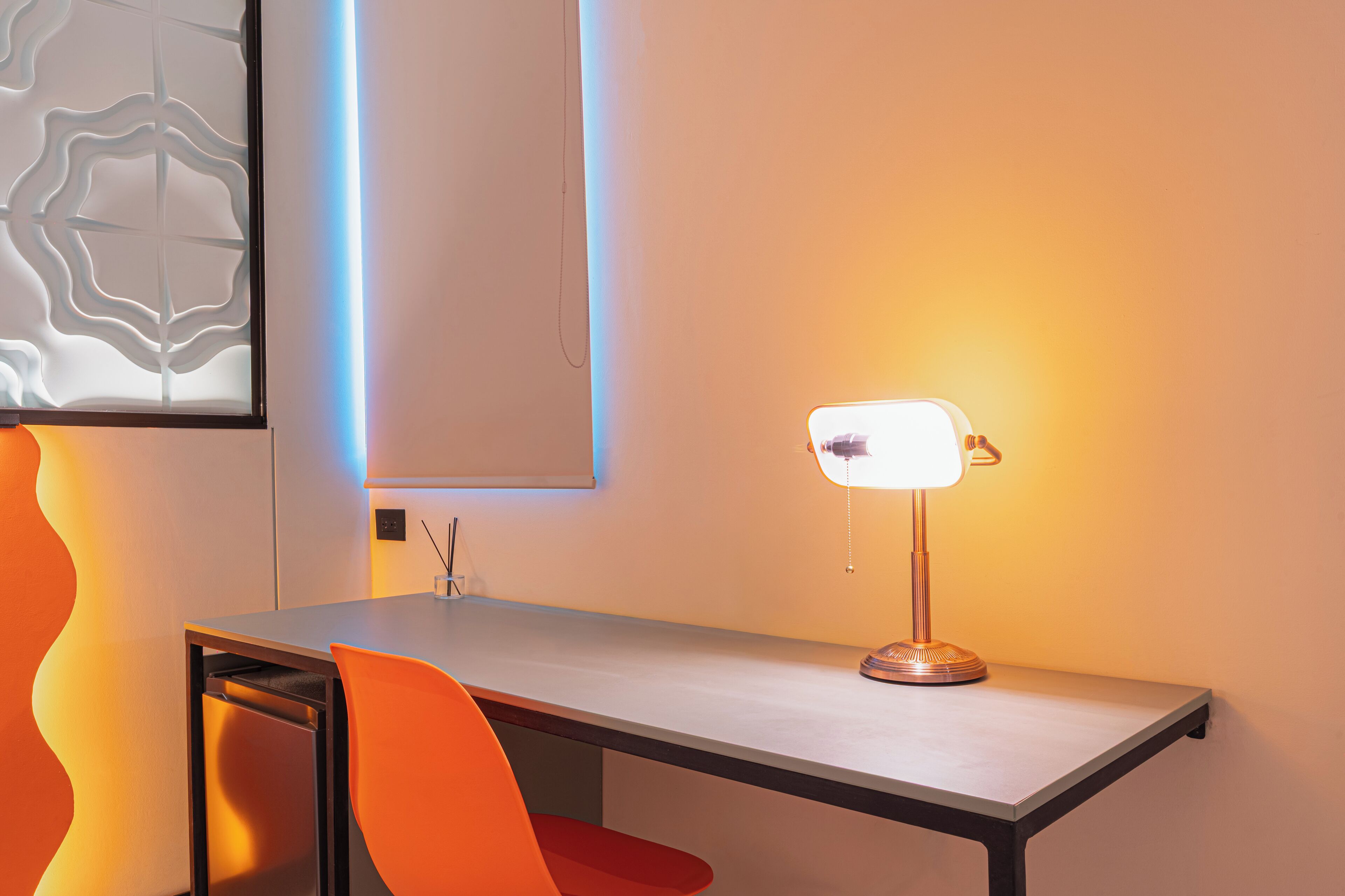 A modern room with a desk, a chair, and a table lamp.