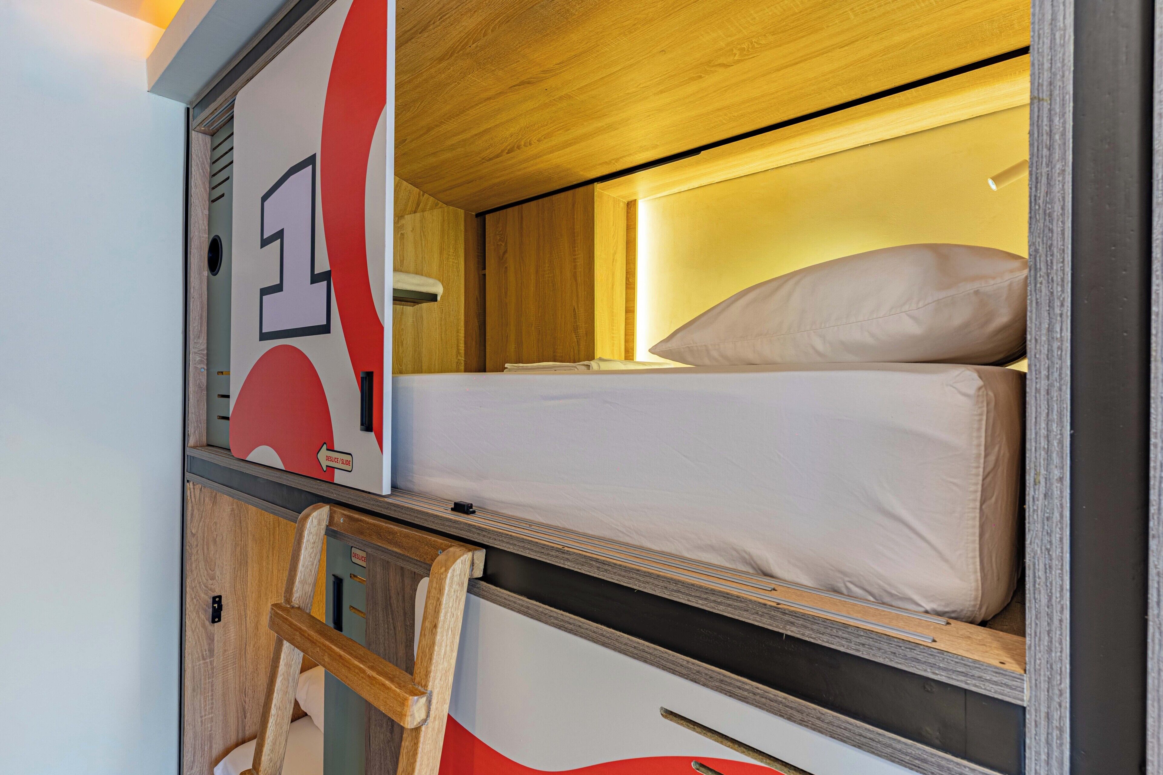 A compact room with a bunk bed, a small desk, and a chair.