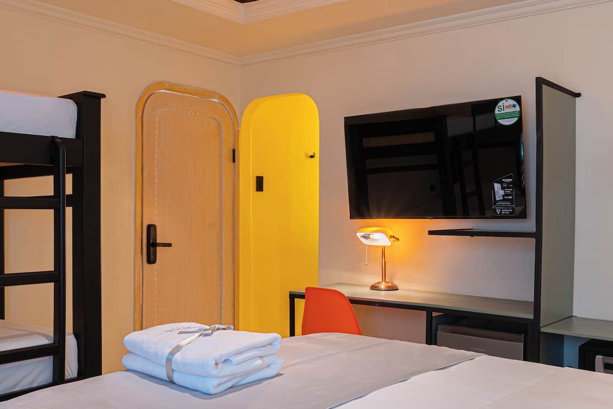 Une chambre d’hôtel avec un lit superposé, un bureau avec une lampe et un téléviseur.