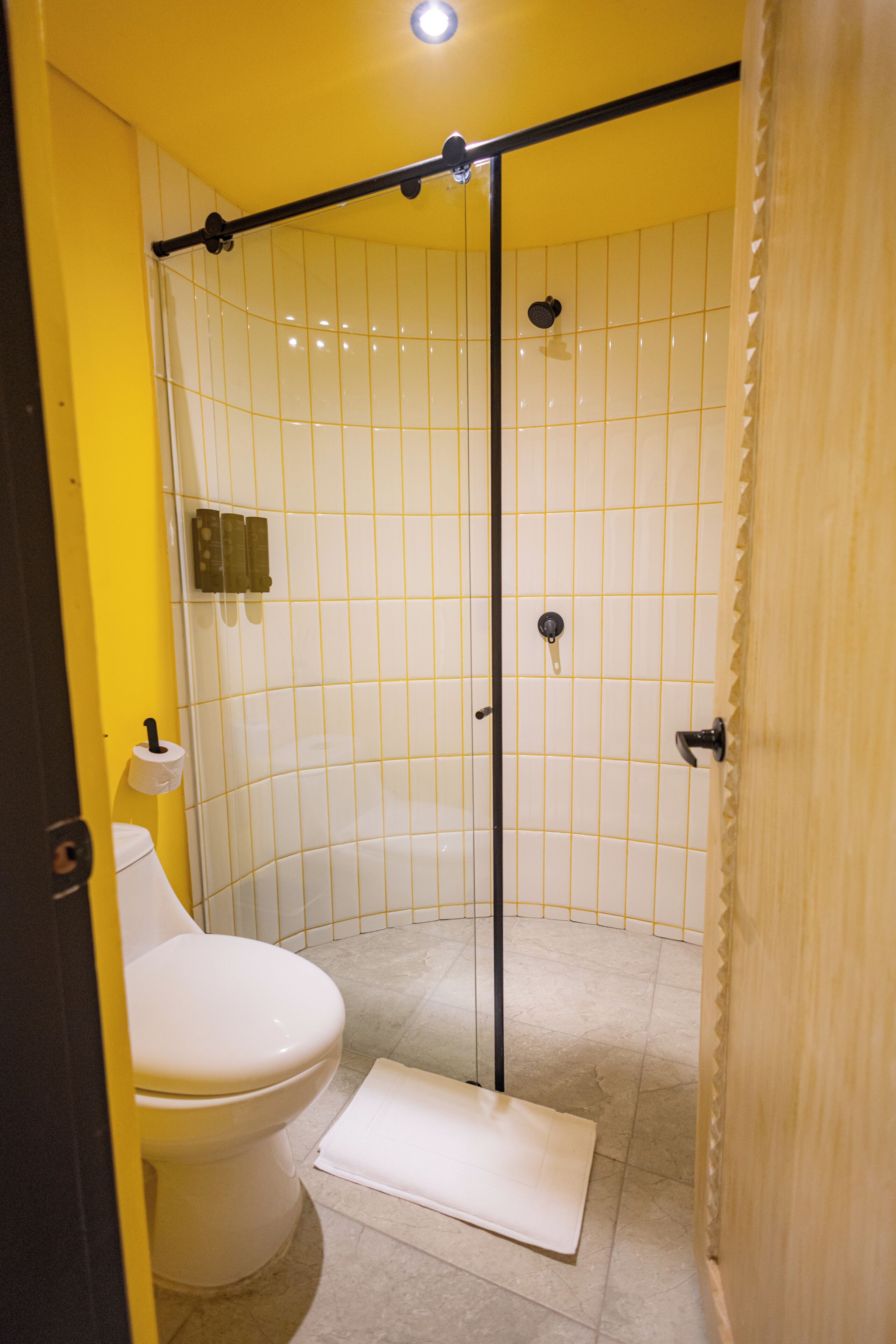 A bathroom with a white toilet, a shower stall, and yellow walls.