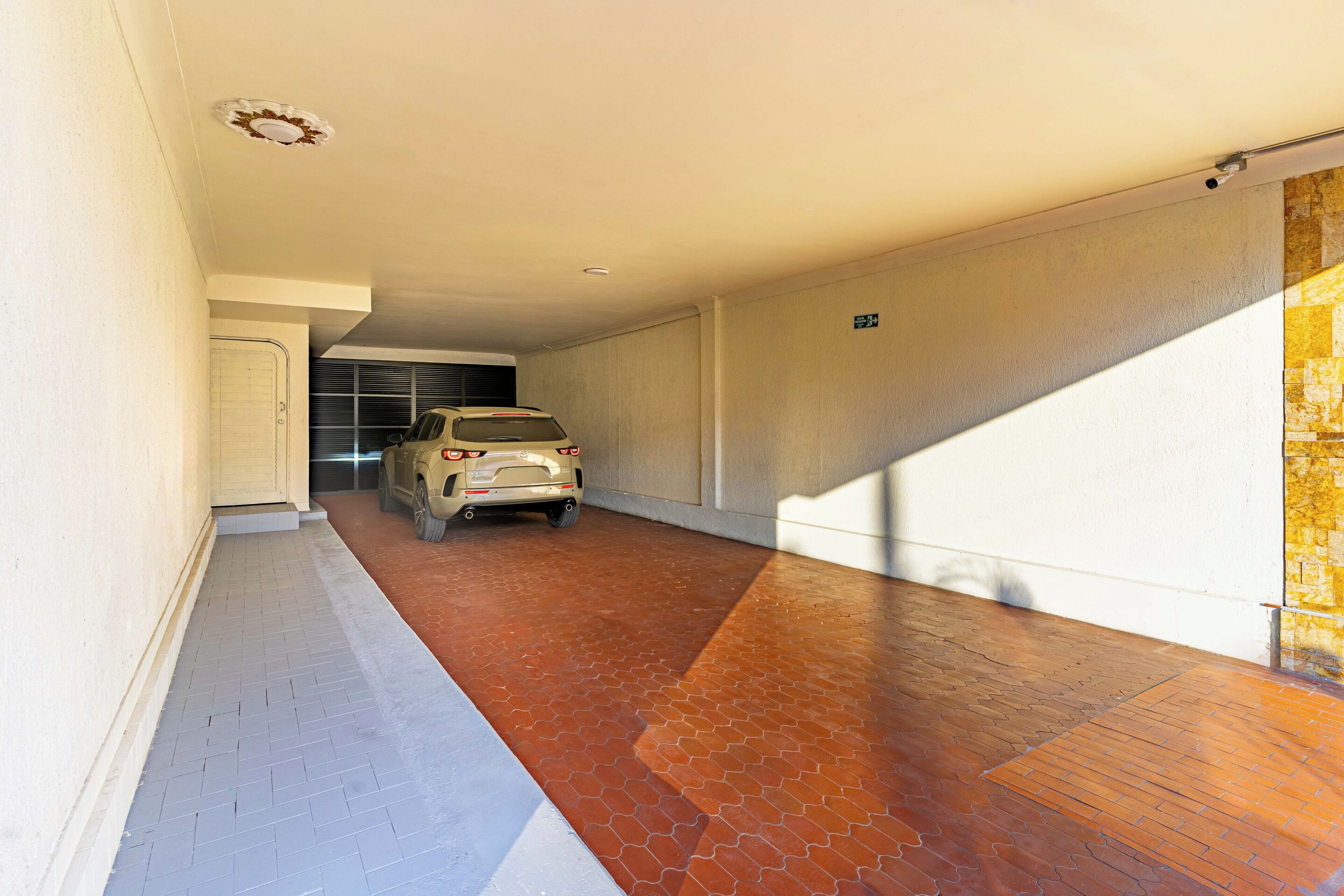 A vehicle parked in a narrow hallway with a tiled floor, a door, and a wall with a sign.