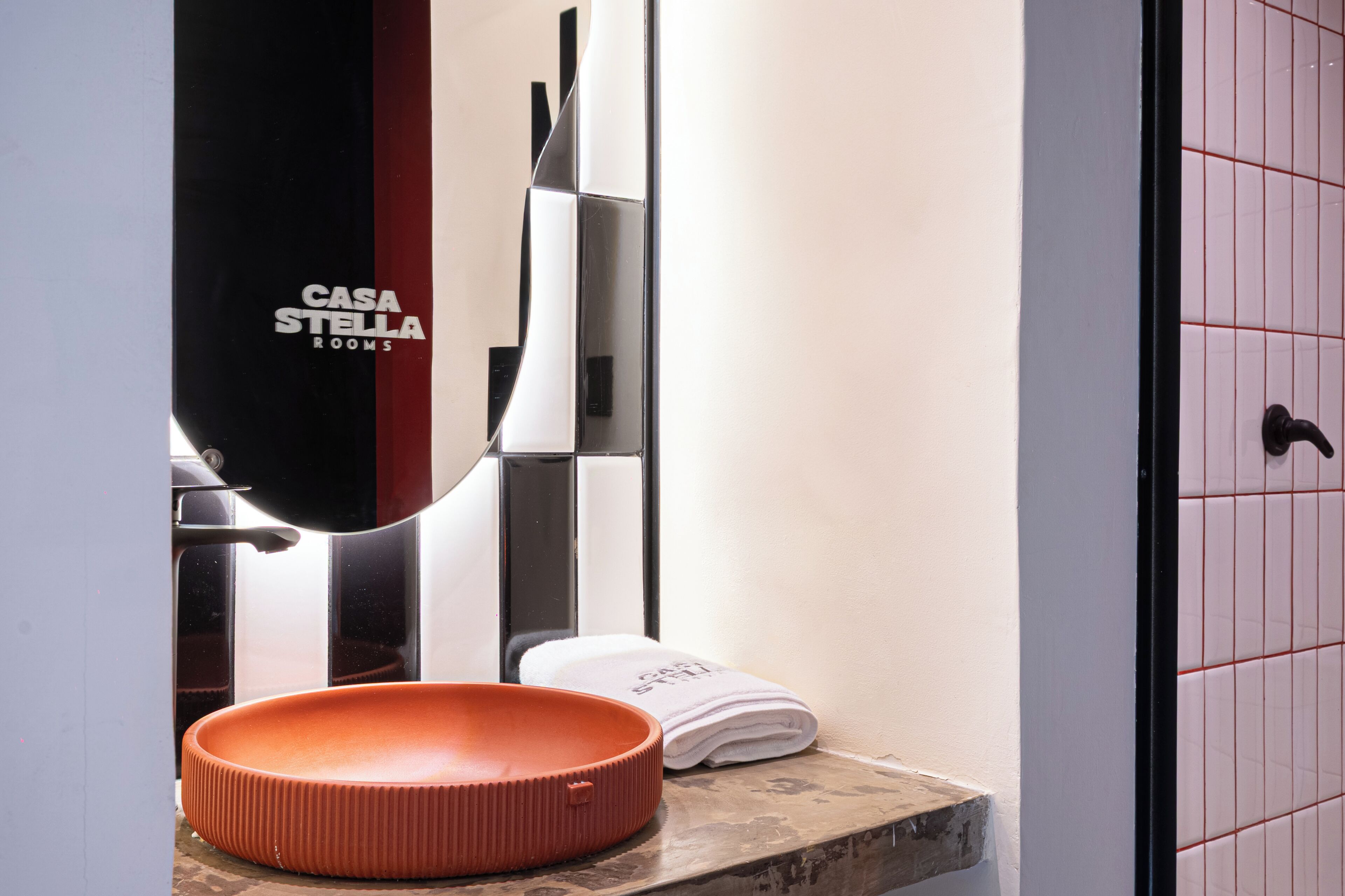 A bathroom with a round sink, a towel, and a mirror.