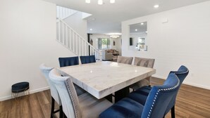 Uma sala de jantar com uma mesa de mármore, cadeiras estofadas em azul e um candelabro.
