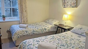A bedroom with two beds, a window with curtains, a lamp, and a painting on the wall. - 3 bedroom accommodation in Osmotherley, near Brompton (Osmotherley, near Brompton)