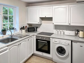 A kitchen with white cabinets, a Bosch dishwasher, a microwave, a toaster, and a sink.