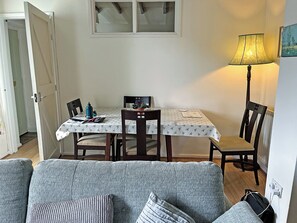 A dining area with a table, chairs, a lamp, and a sofa.