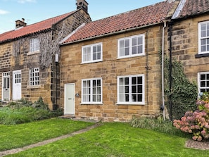 A stone building with multiple windows and a red-tiled roof.