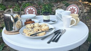 A round outdoor table with a white tablecloth, a metal kettle, a plate of scones, a cup of coffee, a mug, a jar of jam, and a slice of cake. - 3 bedroom accommodation in Osmotherley, near Brompton (Osmotherley, near Brompton)
