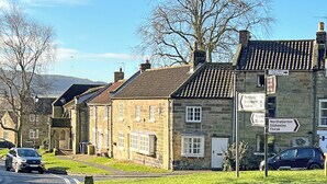 A stone building with a traditional design, a signpost with directions, and a road with cars. - 3 bedroom accommodation in Osmotherley, near Brompton (Osmotherley, near Brompton)