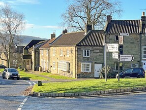 A stone building with a traditional design, a signpost with directions, and a road with cars.