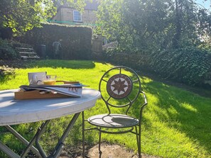 A round table with a chair, a glass of orange juice, and a book.