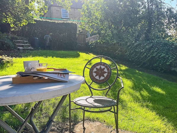 A round table with a chair, a glass of orange juice, and a book.