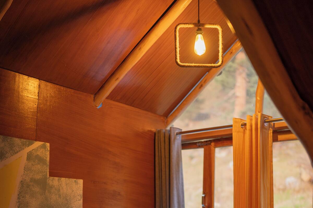 Una habitación acogedora con una cama, una mesa y un ventanal con cortinas.
