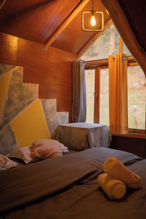 A cozy room with a bed, a table, and a window with curtains.
