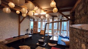 A rustic interior with wooden beams, paper lanterns, and a view of the outdoors. - The Hidden Treasure (Sosan)