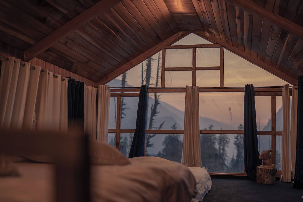 Un dormitorio con un ventanal grande, techo de madera y una cama.