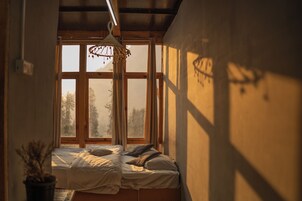 Una habitación con una cama, una lámpara colgante y un ventanal con cortinas.