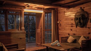 A wooden interior with a sofa, a bench, and a Buddha statue. - The Hidden Treasure (Sosan)