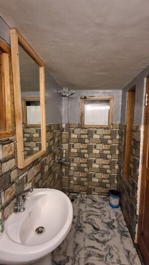 A bathroom with a white sink, a mirror, stone-patterned walls, and a tiled floor.