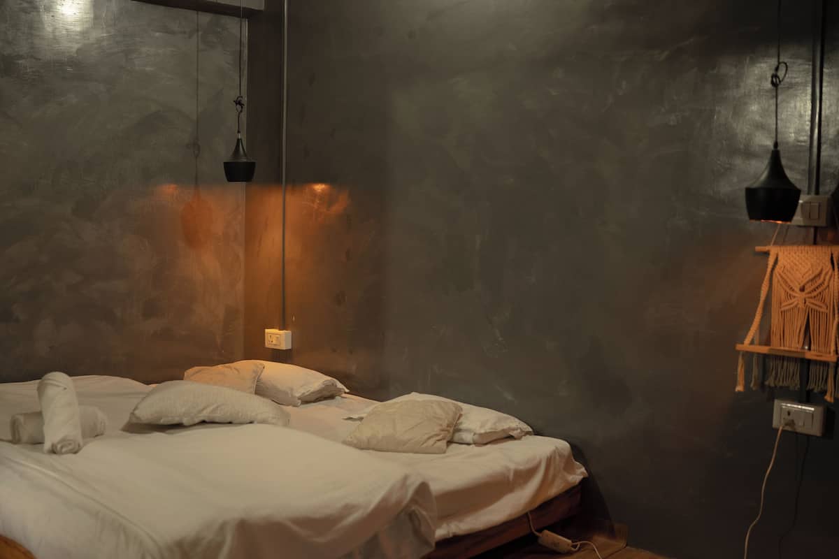 Una habitación con una cama, un adorno de macramé en la pared y una lámpara colgante.