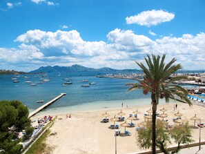 A beach with clear blue water, boats, and a mountain in the background. - La Salve Can Jordi by Interhome (Pollença)