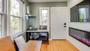 A compact kitchen with a built-in microwave, oven, and toaster, a wooden dining table, and a fireplace with a visible fire. - Commuter's Dream! Cheverly Studio 1/2 Mi to Metro (Cheverly)