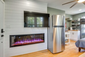 A modern kitchen with a built-in fireplace, stainless steel appliances, and a wooden floor.