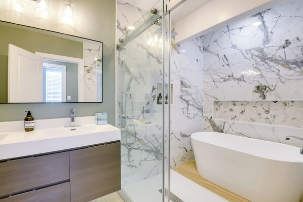 A modern bathroom with a glass-enclosed shower, a white sink, and a marble backsplash.