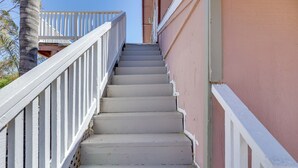 Una serie de escaleras blancas con barandilla, que conducen a un balcón.