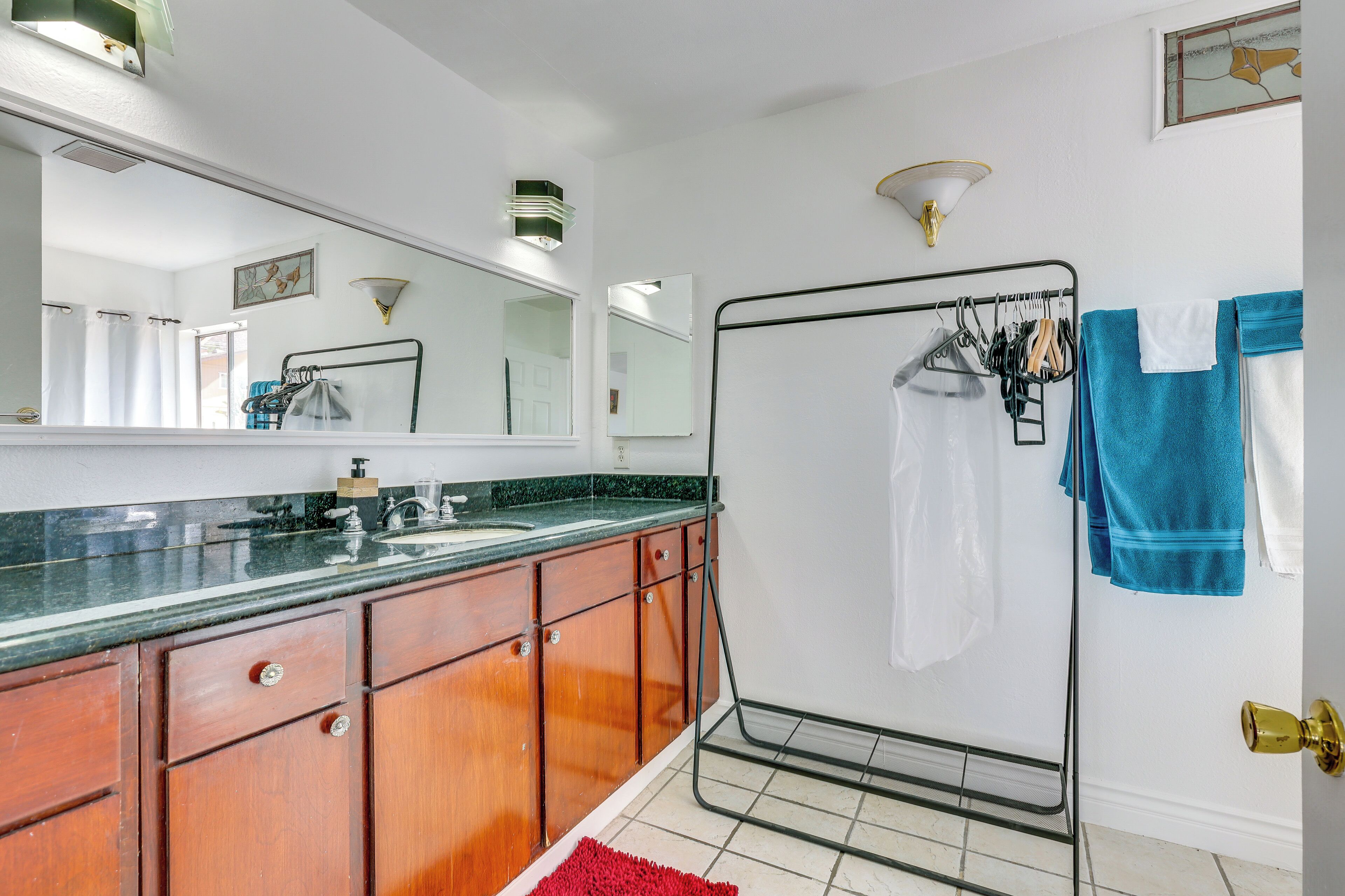 Un baño con armarios de madera, un lavamanos, un espejo, un perchero para toallas y una zona de ducha.