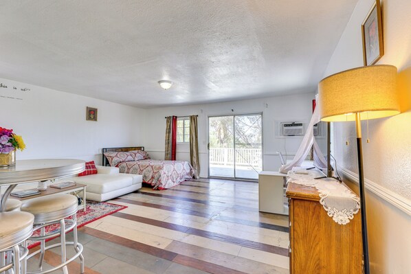 Une pièce spacieuse comprenant un lit, un canapé blanc, une table à manger avec des chaises et un buffet en bois.