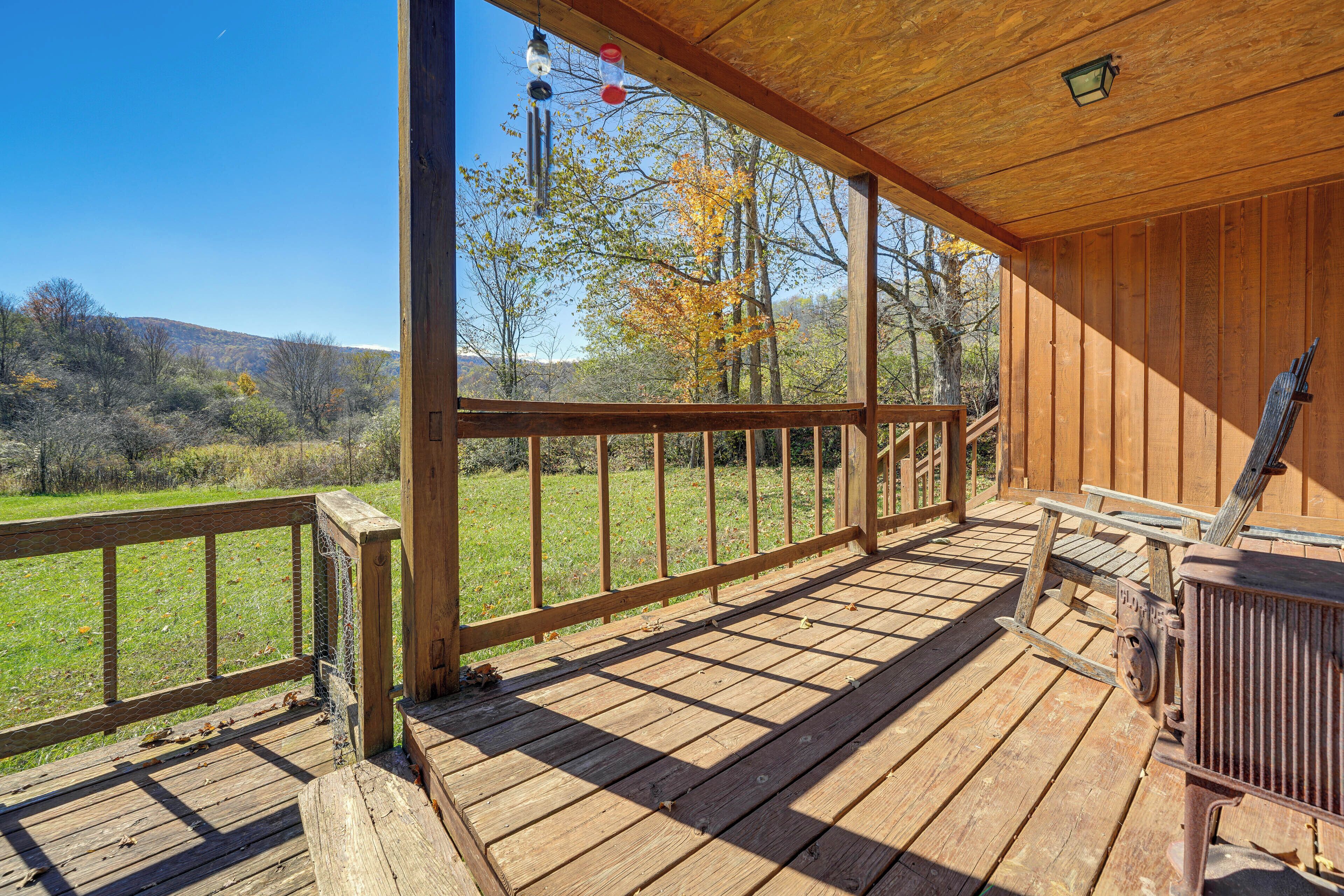 A wooden deck with a view of a grassy field and trees.