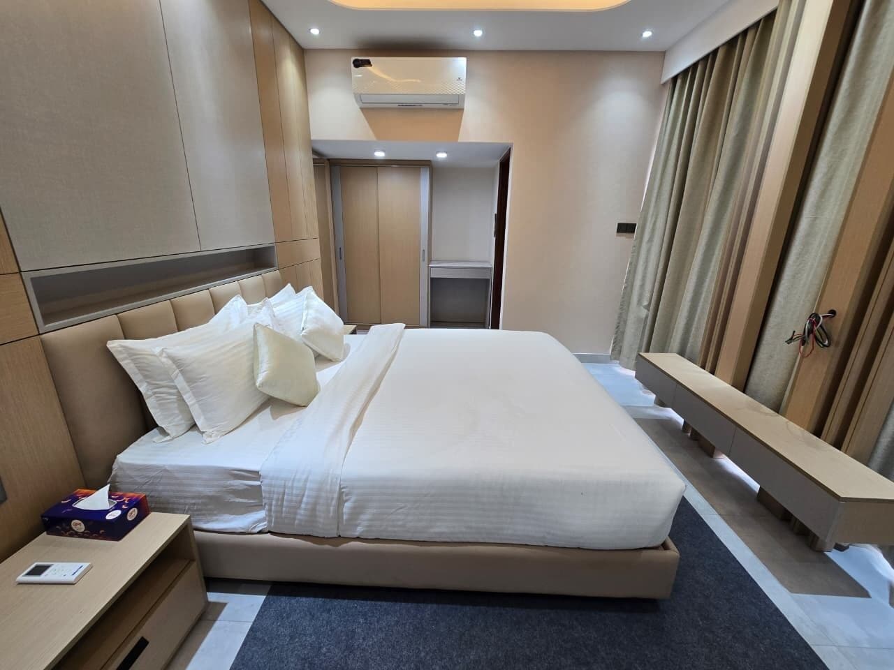 A hotel room with a bed, bedside table, and a small desk.