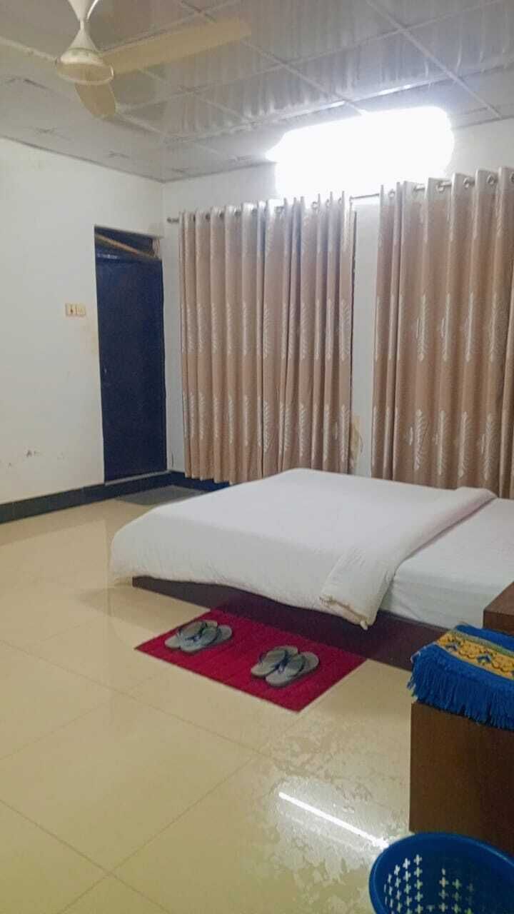 Una habitación con cama, ventilador de techo, puerta y cortinas.