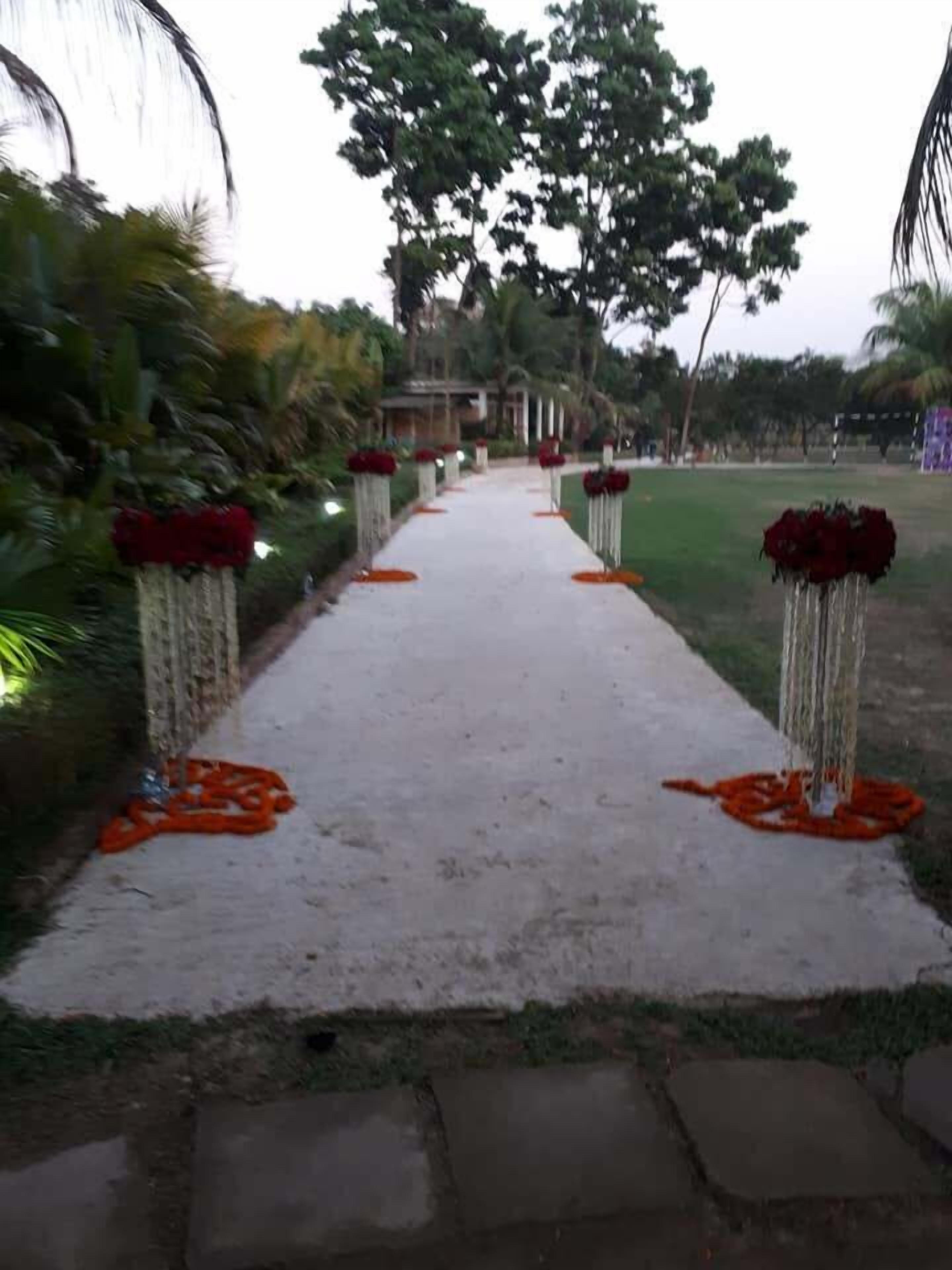 A pathway with red flowers and greenery on either side.
