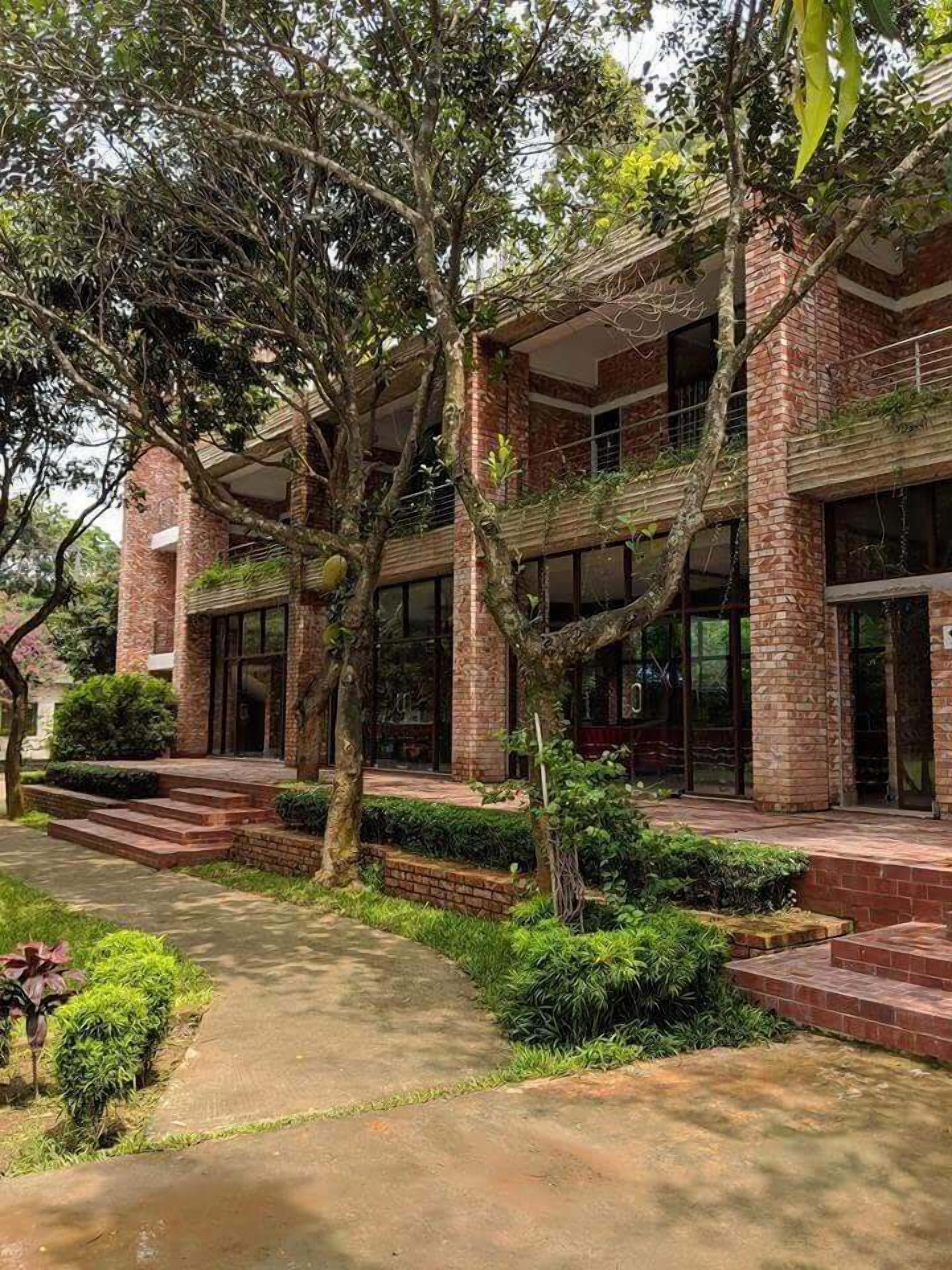 A building with a brick facade, large windows, and a pathway leading to the entrance.