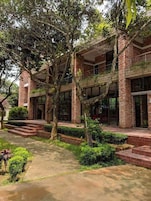 Un edificio de fachada de ladrillo, con amplias ventanas y un camino que lleva a la entrada.