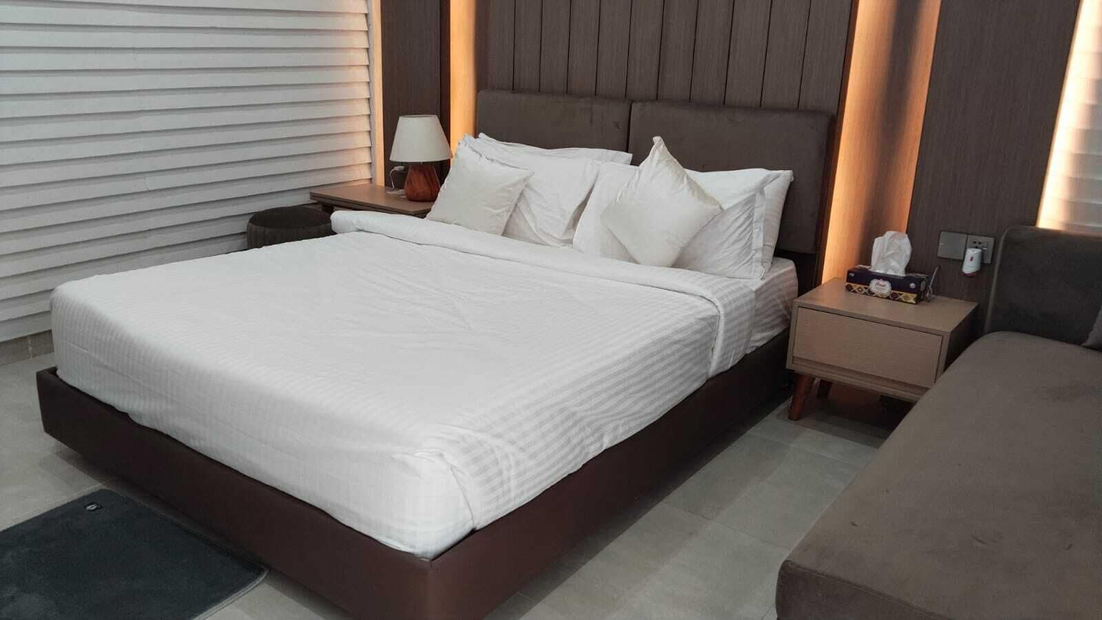 Une chambre d’hôtel moderne avec un grand lit, des tables de chevet et une petite table de nuit.