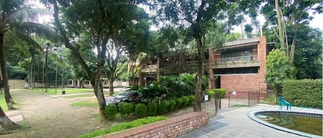 Une cour avec un mur en briques, une piscine et un bâtiment doté d’un balcon.