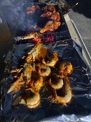 A grill with various meats and shrimp being cooked. - Global Inn Hostel (Kuala Lumpur)