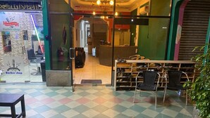 Eine Hotelhalle mit einer Rezeption, einem Friseursalon und einer Sitzecke mit Stühlen.