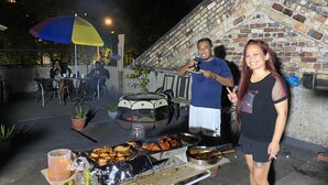 Ein draußen aufgebautes Barbecue mit Grill, Speisen und einem Tisch mit Getränken.