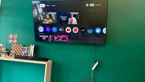 Ein Flachbildfernseher an einer grünen Wand, der eine Streaming-Oberfläche mit verschiedenen Apps und einem Spiel zeigt.