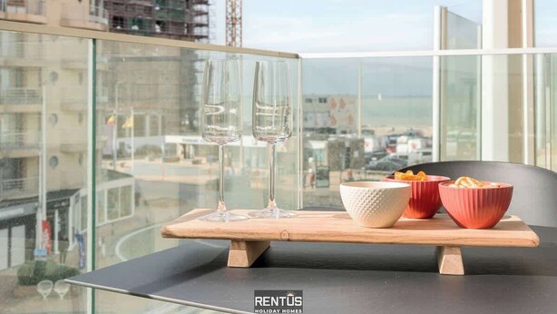 Un balcone con un tavolo apparecchiato per due persone, con due bicchieri e una ciotola di snack.